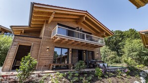 Una moderna casa a due piani con facciata in legno, un balcone e un giardino.