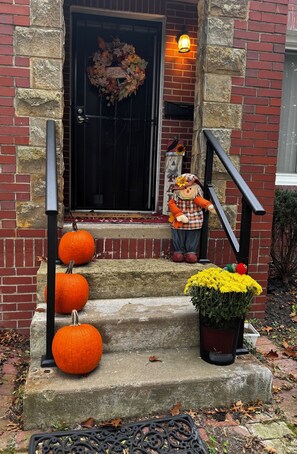 A brick house with a black door, a wreath, and a scarecrow on the steps. - Charming 3-bedroom house in serene Youngstown 5 minutes from shopping district. (Youngstown)