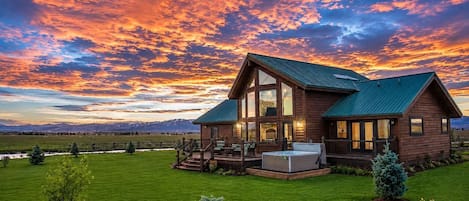 Una cabaña de madera con terraza, jacuzzi y un paisaje montañoso.