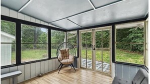 Et solrum med store vinduer, en hængestol, en bænk og en sofa.