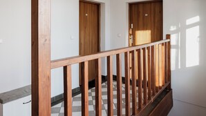 A hallway with wooden doors, a wooden railing, and a tiled floor. - Toruń Studzienna Cozy Urban Studio (Toruń)
