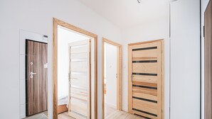A hallway with three wooden doors, a white wall, and a wooden floor. - Lubicka 69 Urban Retreat Apartment (Toruń)