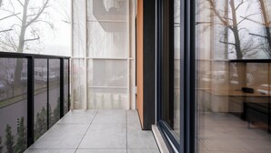 Un balcone moderno con vista su alberi e un edificio sullo sfondo.