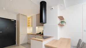 Una cucina moderna con una porta nera, mobili bianchi, un piano di lavoro in legno e una cappa aspirante nera.
