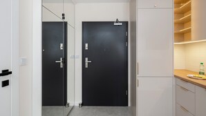 Una cucina moderna con due ante nere, un armadietto bianco con forno integrato e un piano di lavoro in legno con una bottiglia d'acqua.
