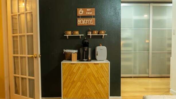 Ein Zimmer mit einem Holzkasten, einer Kaffeemaschine und einem Schild an der Wand.