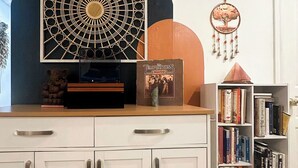 Ein Zimmer mit einem weißen Schrank, einem Bücherregal, einer Wanddekoration und einem Traumfänger.