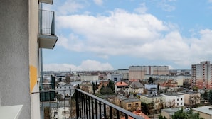 En balkong med utsikt över en stadsbild, inklusive bostadshus och en avlägsen skyskrapa.