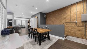 A modern kitchen with a wooden accent wall, a dining area with a wooden table and chairs, and a visible kitchen island.