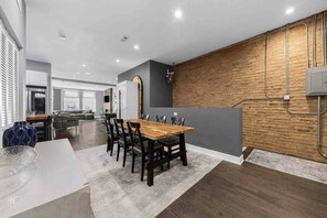 Eine moderne Küche mit einer Holzwand, ein Essbereich mit Holztisch und Stühlen sowie eine sichtbare Kücheninsel.