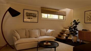 A living room with a sofa, a coffee table, a lamp, a plant, and artwork on the walls.