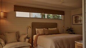 A bedroom with a large bed, a sofa, a bedside table, a lamp, and a window with blinds. - 28 Degrees Byron Bay - Adults Only (Byron Bay)