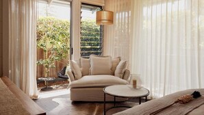 A modern living room with a sofa, a round coffee table, and a hanging light fixture. - 28 Degrees Byron Bay - Adults Only (Byron Bay)
