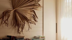 A room with a large wall-mounted plant, a wooden console table with books, and a window with sheer curtains. - 28 Degrees Byron Bay - Adults Only (Byron Bay)