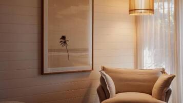 Una habitación de hotel acogedora con cama, una silla, una mesita pequeña y un ventanal con cortinas traslúcidas.