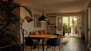 A modern dining area with a round wooden table, black chairs, and a hanging pendant light. - 28 Degrees Byron Bay - Adults Only (Byron Bay)