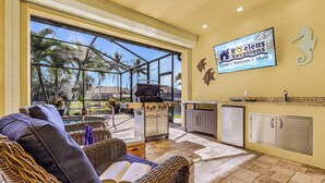 Un'ampia zona relax esterna con mobili in vimini, un barbecue e vista su palme.