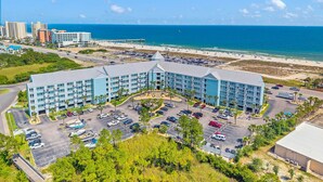 Hotel com pátio central, estacionamento e vista para a praia e o oceano.