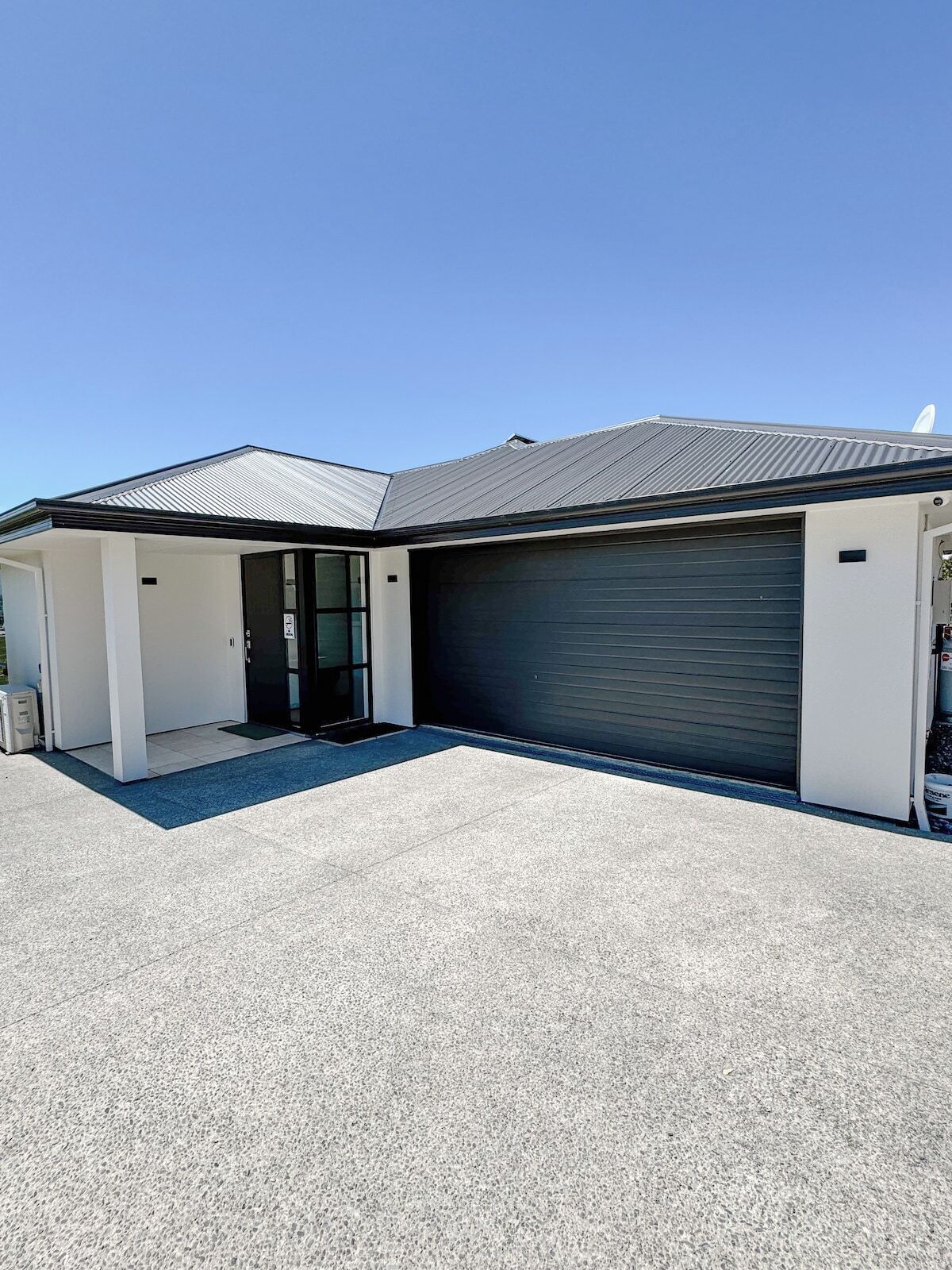 A modern building with a garage door, a covered entrance, and a paved driveway.
