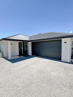 A modern building with a garage door, a covered entrance, and a paved driveway. - The Lake House on Pollock, LakeTekapo (Lake Tekapo)