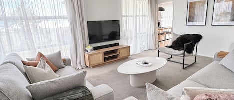 A modern living room with a sofa set, a coffee table, a TV, and a chair.