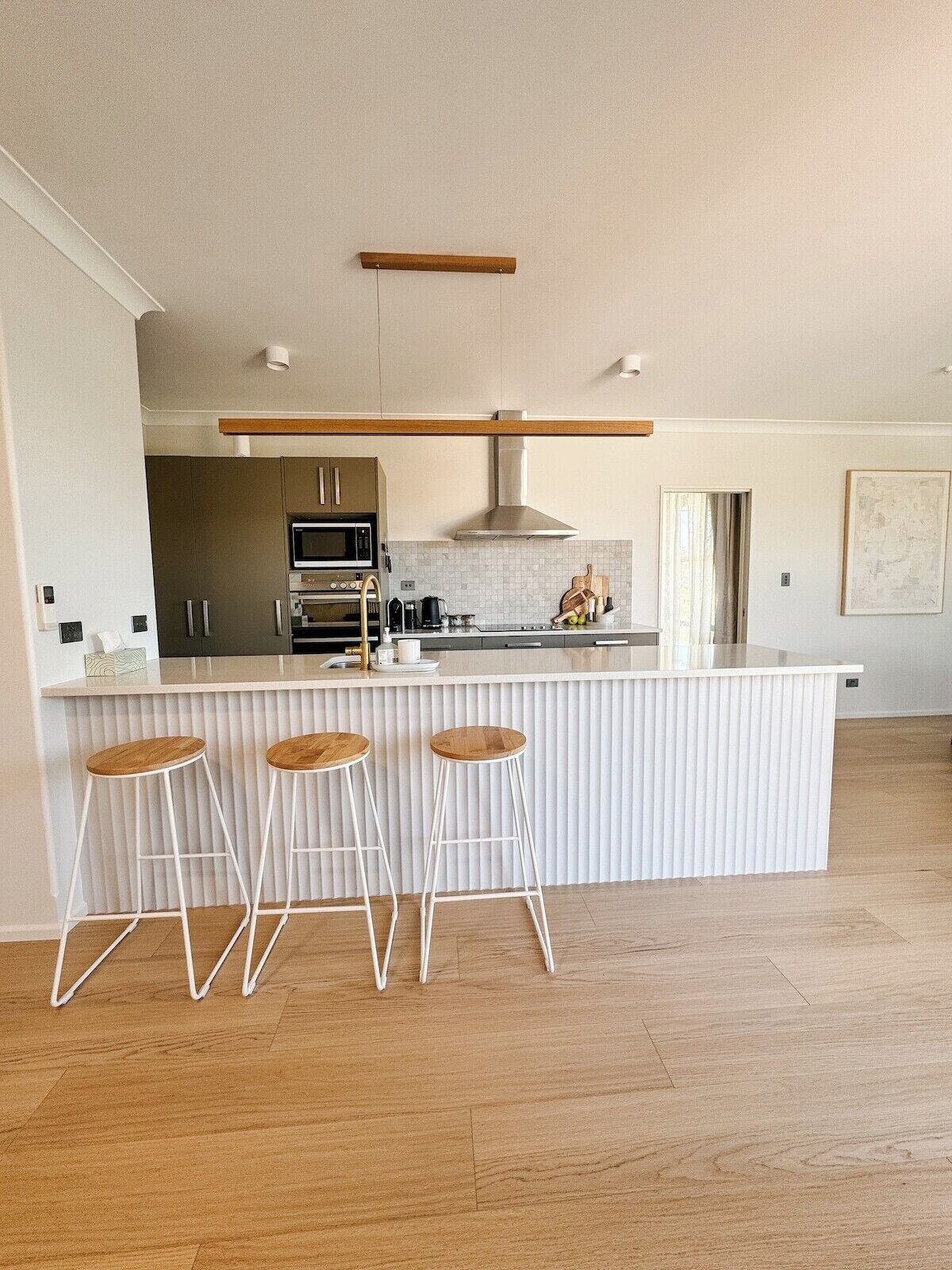A modern kitchen with a central island, bar stools, and stainless steel appliances.