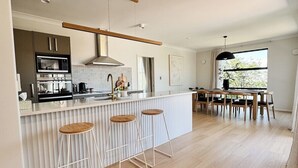 A modern kitchen with a central island, bar stools, and a dining area with a table and chairs.
