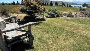 A rustic wooden bench in a grassy field with a mountain and lake in the background.