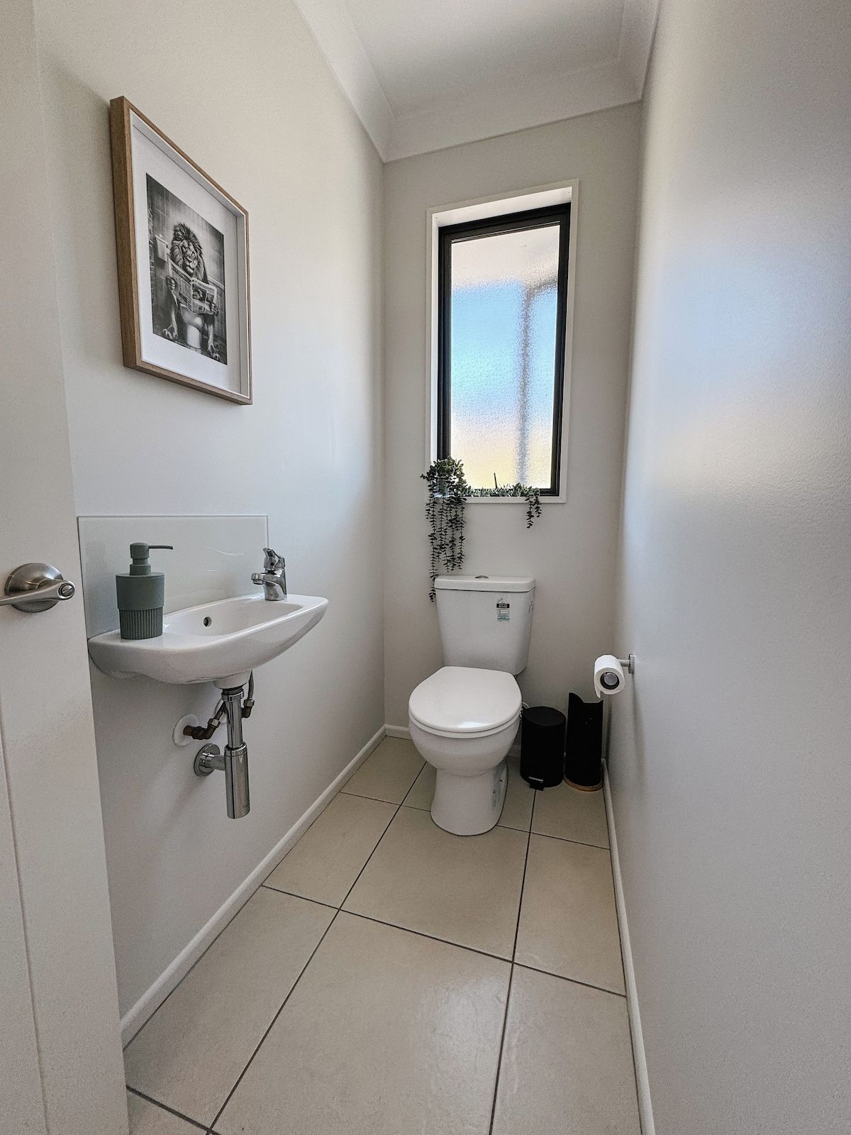 A small, clean bathroom with a white sink, toilet, and a window with a view.