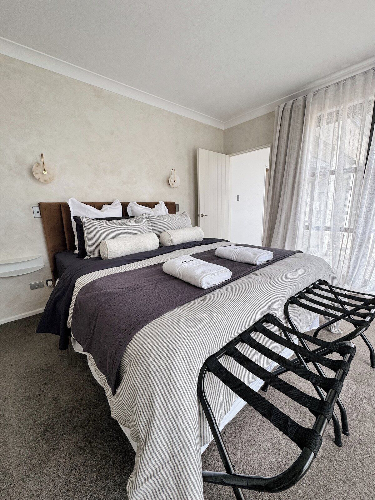A hotel room with a bed, a chair, and a door.