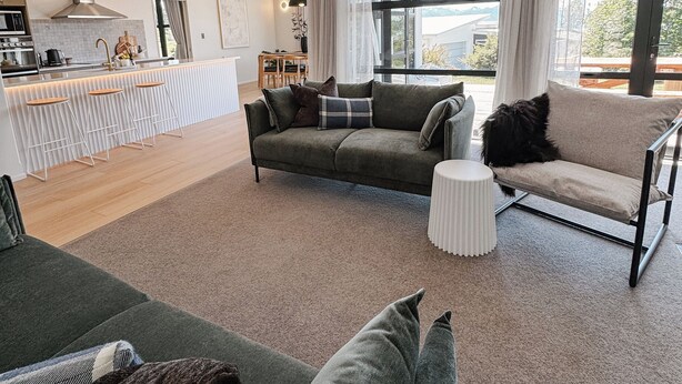 Een moderne woonkamer met een bank, een salontafel en een keuken in de achtergrond.