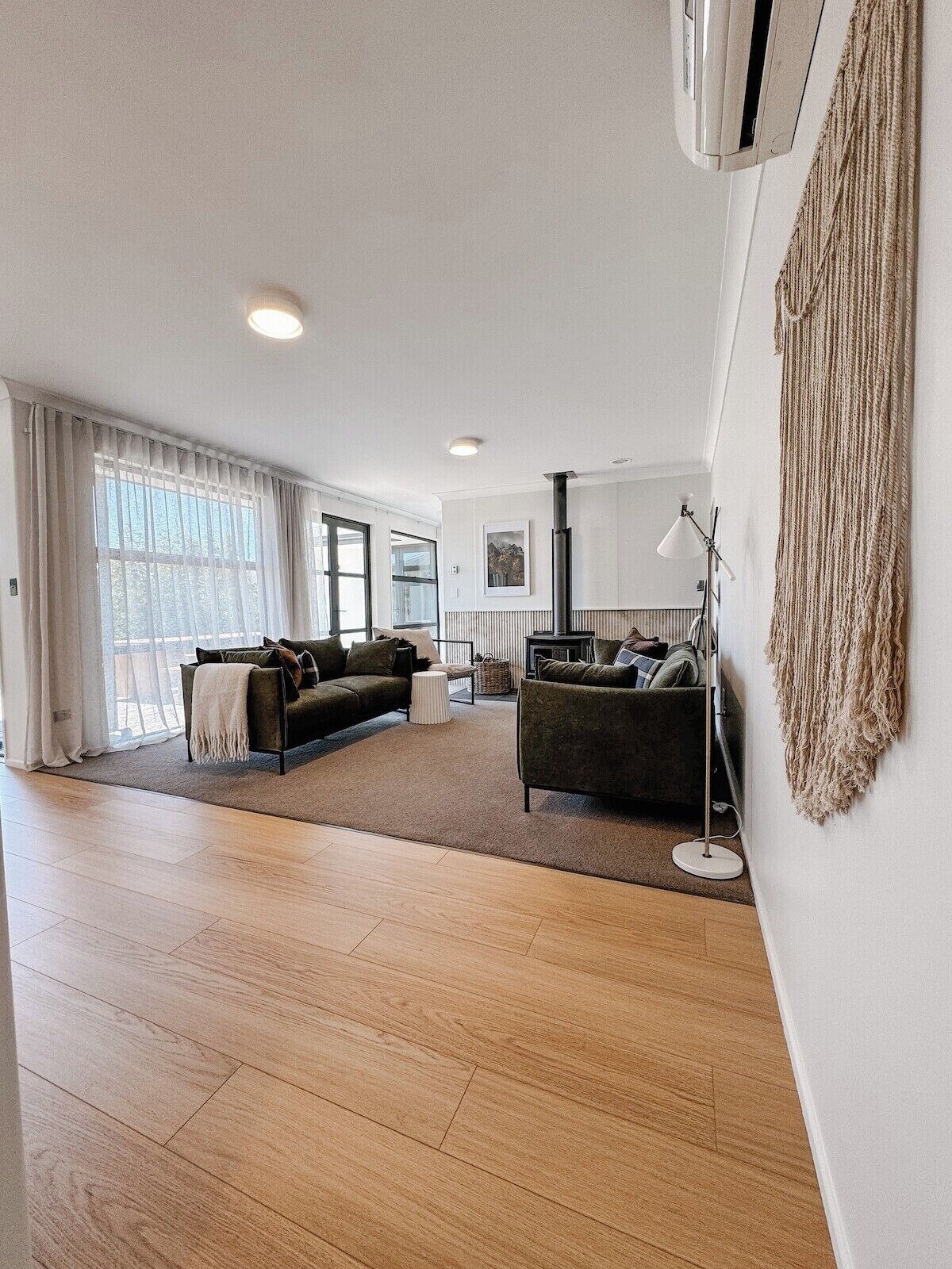 A spacious living room with a large window, a sofa, a coffee table, and a floor lamp.