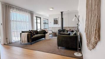 A spacious living room with a large window, a sofa, a coffee table, and a floor lamp.