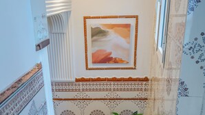 Una escalera con paredes decoradas y una planta en maceta.