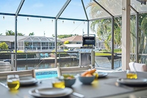 Un espacio de comedor al aire libre con vista a una piscina y una parrilla.