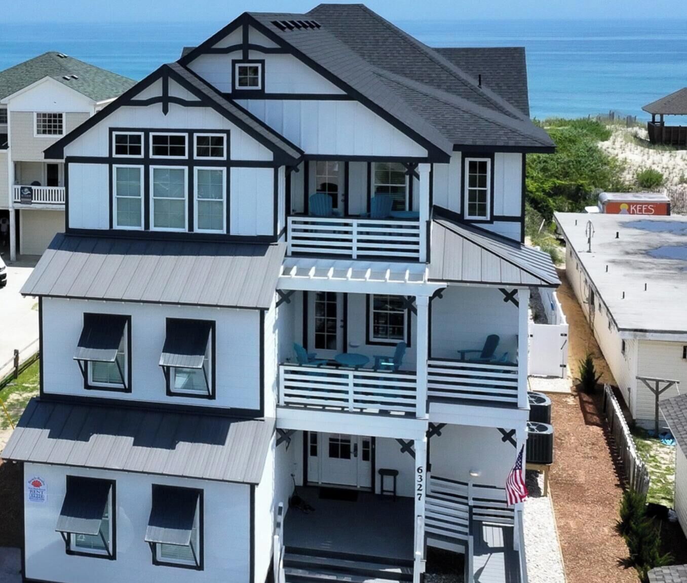 A multi-story house with a balcony on the second floor, a garage, and a view of the ocean.