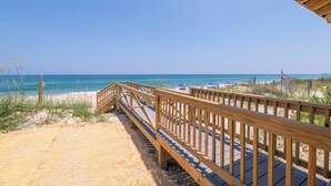 Une promenade en bois menant à une plage, avec un ciel dégagé.