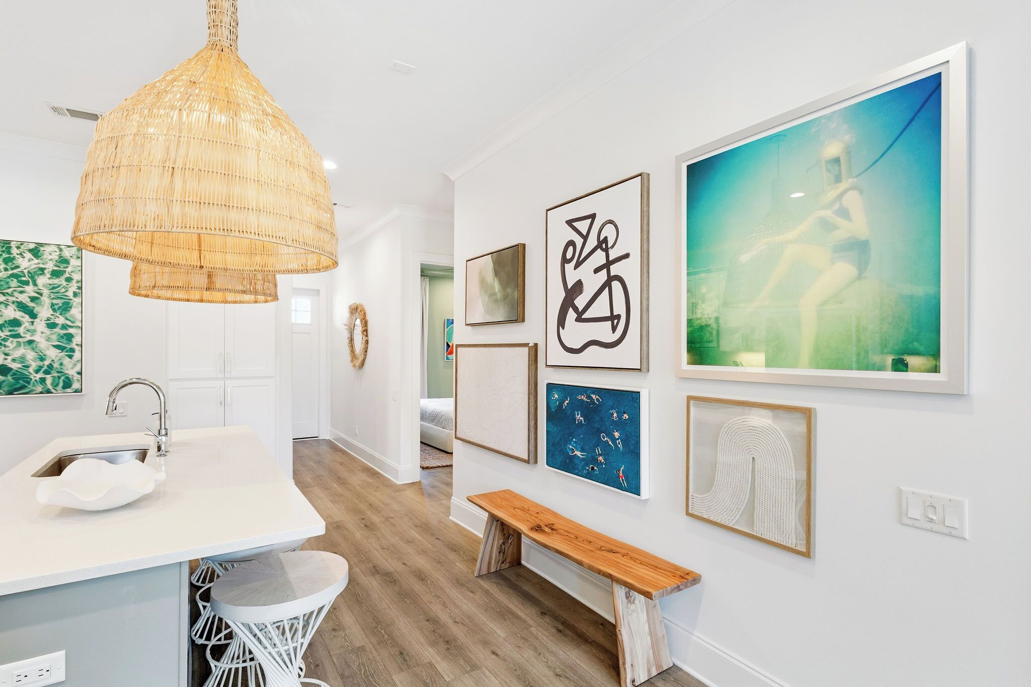 A modern kitchen with a white countertop, a hanging light fixture, and artwork on the walls.