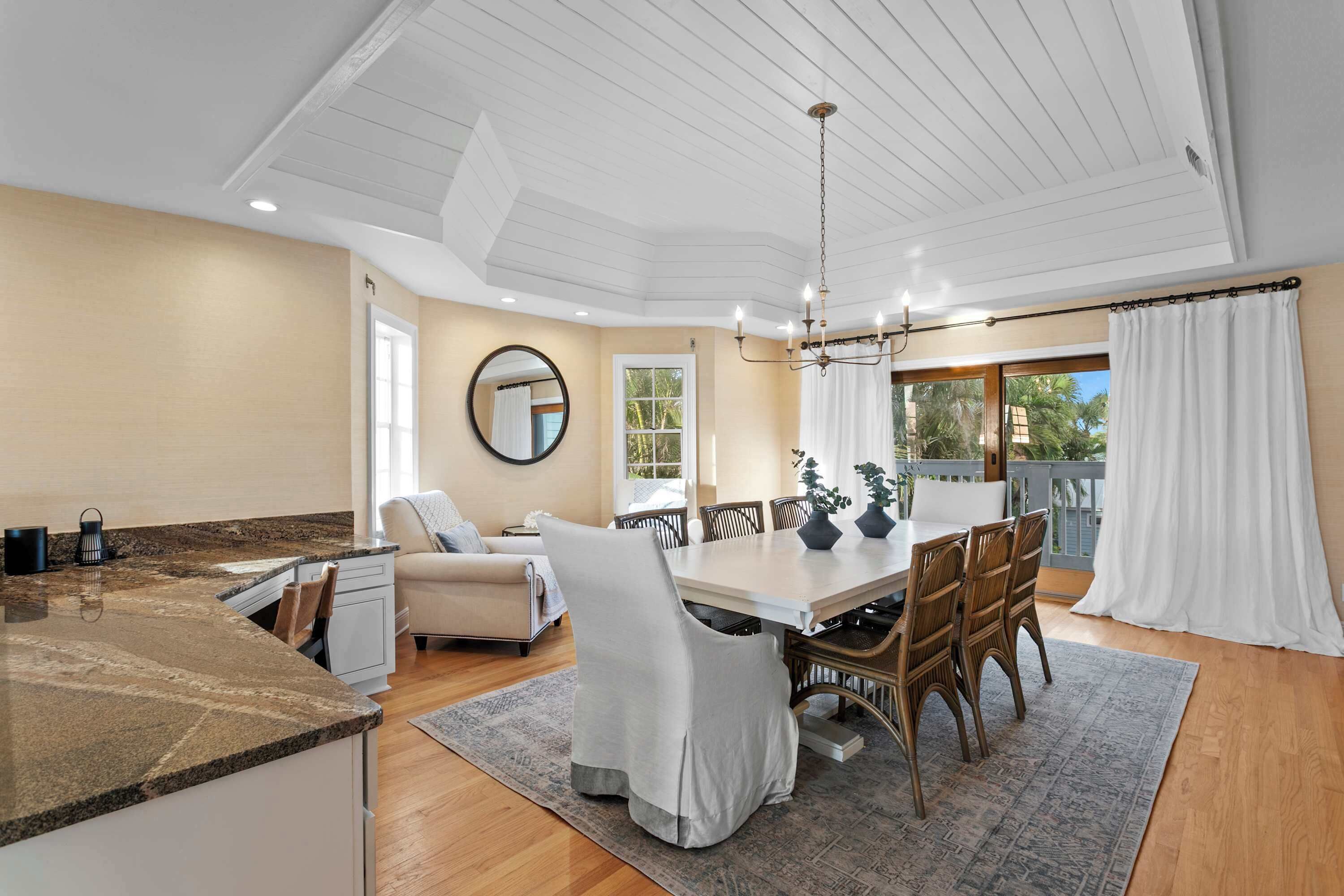 A spacious dining area with a large table, chairs, and a chandelier.
