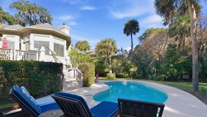 A backyard with a swimming pool, lounge chairs, and a wooden deck. - Beautiful Palmetto Dunes home with bikes, pool, hot tub. (Hilton Head Island)