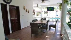 A dining area with a wooden table and wicker chairs, a ceiling fan, and a TV mounted on the wall. - Casa de Campo en San Jose de Río Tinto, Catacamas. (Catacamas)