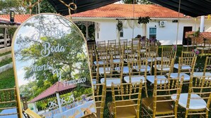 Un salón de bodas con hileras de sillas doradas y una carpa.