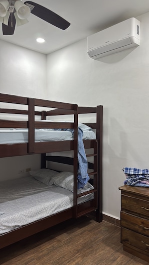 Una cama individual superpuesta con ventilador de techo y aire acondicionado.