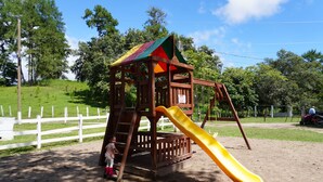 A wooden play structure with a slide in a park.