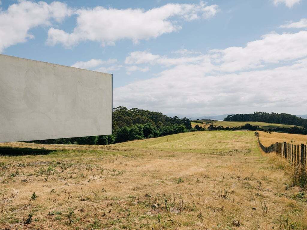 A large, blank billboard in a rural landscape with rolling hills and a clear sky.