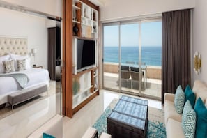 Ein Hotelzimmer mit Bett, Fernseher, Balkon mit Tisch und Stühlen sowie Meerblick.