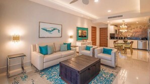 A modern living room with a sofa set, a coffee table, and a dining area with a chandelier. - Garza Blanca Cancun 2BR Suite Full Kitchen 
1980 avg. sq. ft.
Max:6 guests (Cancún)