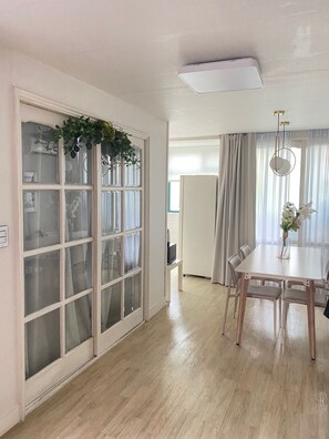A modern living room with a sliding glass door, a dining table with chairs, and a hanging light fixture. - 4min from Hongdae Univ Station/Seoul/4bed/3room (Seoul)