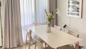 Ein stilvolles Esszimmer mit einem weißen Tisch, beigen Stühlen und einer Blumenvase.