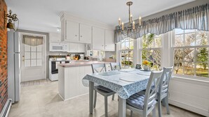 Una cocina moderna con armarios blancos, una isla central y un comedor con mesa y sillas.